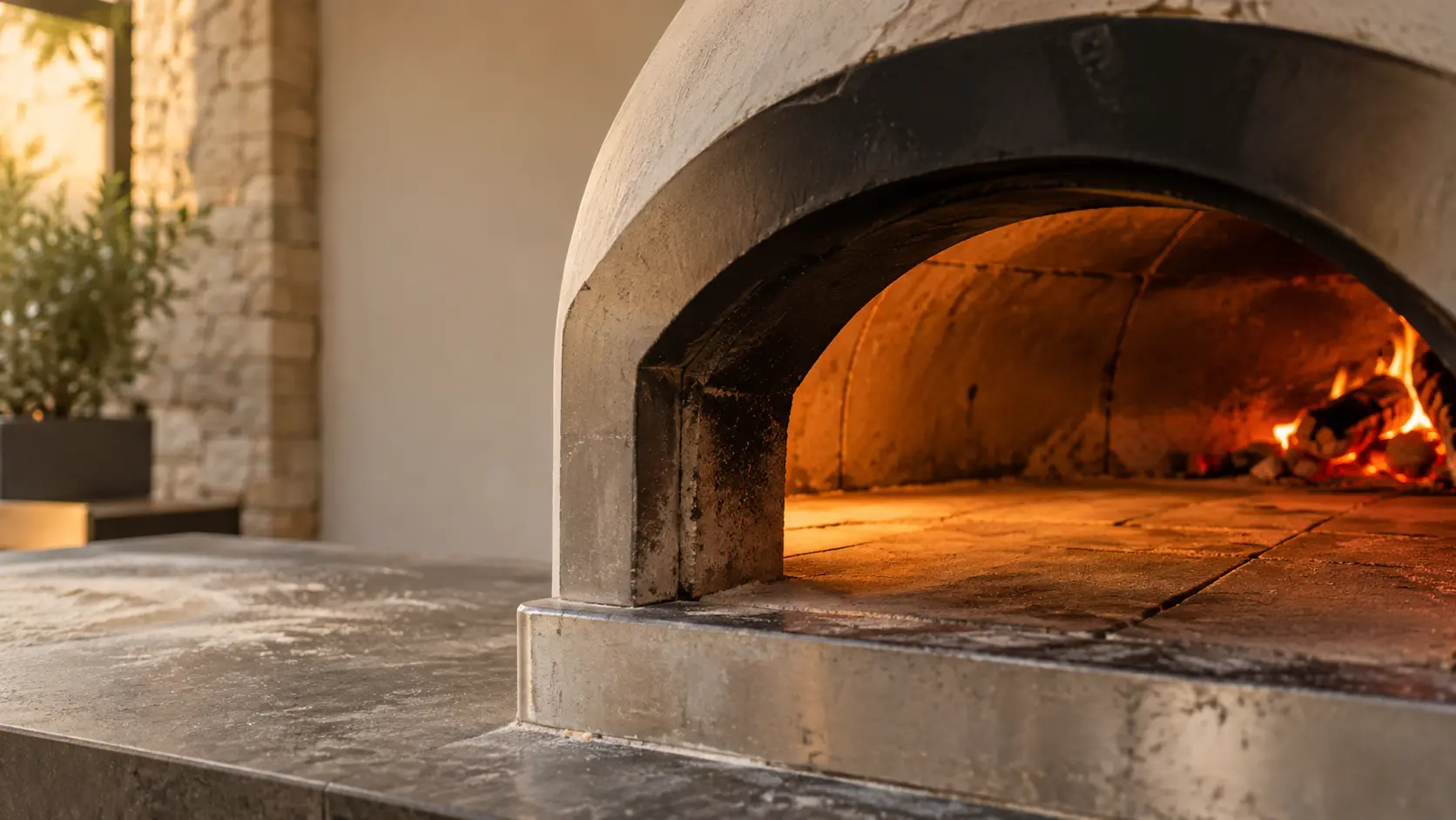 The arched mouth and stone floor of a pizza oven filling the frame, soft light.